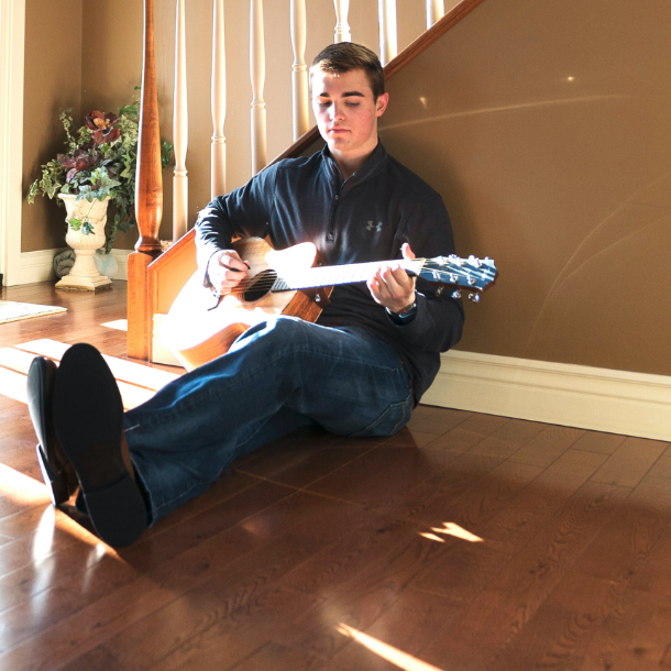 Person sitting on floor playing the guitar